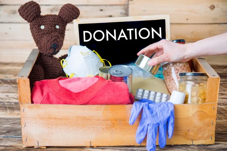 Donation box with clothes, food items, medical supplies, and a teddy bear for charity support